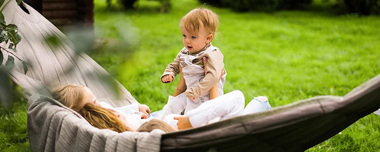 une personne berce un bébé dans un hamac, dans le jardin, le mouvement de bercement crée une expérience unique
